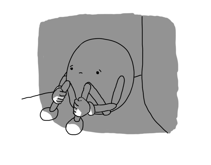 A sad, round robot with jointed limbs, sitting behind a sofa in the dark, arms wrapped around its legs.