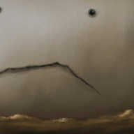 A barren, rocky landscape, rendered in dirty browns beneath a similarly-toned sky fading into darkness high above. The horizon curves slightly upwards and two tiny, dark figures are visible to one side. Looming over everything is an enormous, round robot, coloured pale brown. It stares blankly into the distance with hollowed-out eyes above a ragged slash of a mouth that spans more than half its visible diameter.